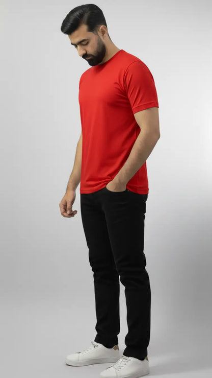 Man wearing a red t-shirt and black pants on a gray background